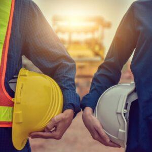 two workers holding helmets